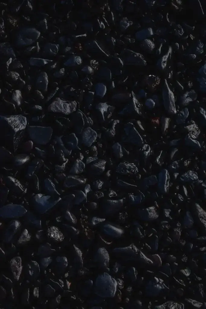 Textured close-up of dark pebbles forming a natural abstract pattern.