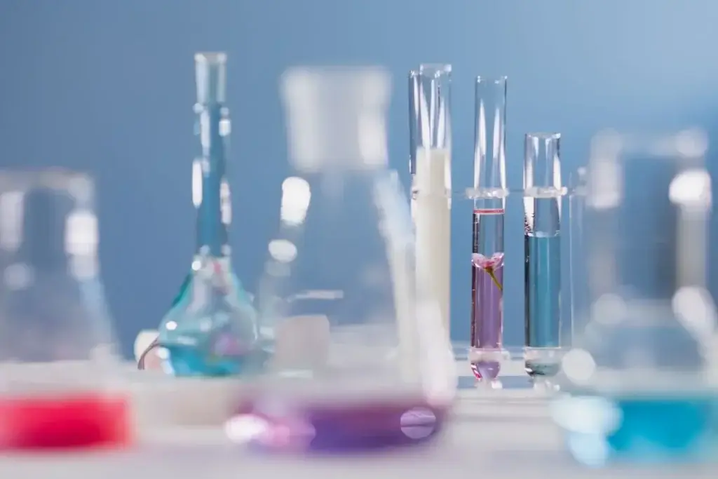 Nahaufnahme verschiedener Glasgeräte mit bunten Flüssigkeiten in einer Laborumgebung.