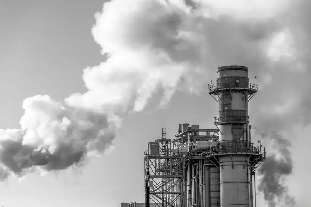 Monochrome image of industrial smokestack releasing steam into the sky.