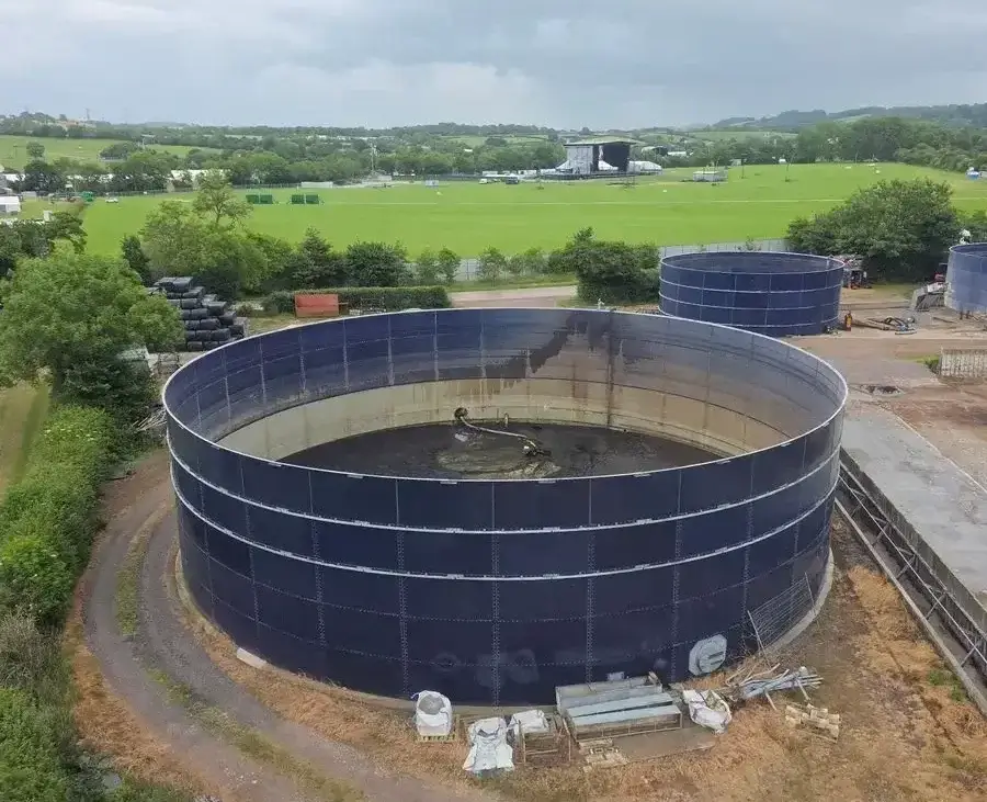 Aerial view of large circular water tanks at an industrial site amidst rural fields.