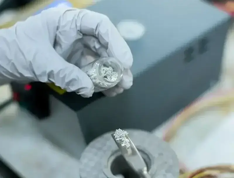Close-up of a scientist handling metal samples in a laboratory experiment with precision tools.